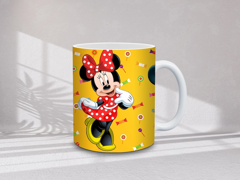 Może przedstawiać: Biały ceramiczny kubek z Minnie Mouse w czerwonej sukience w kropki i kokardą. Kubek ma ż&oacute;łte tło z ilustracjami cukierk&oacute;w i lizak&oacute;w. Uchwyt jest biały.