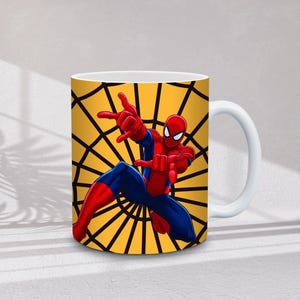 May include: White ceramic mug featuring a colorful illustration of Spider-Man in a dynamic pose. The background is a yellow spiderweb design. The superhero is depicted in his classic red and blue suit.