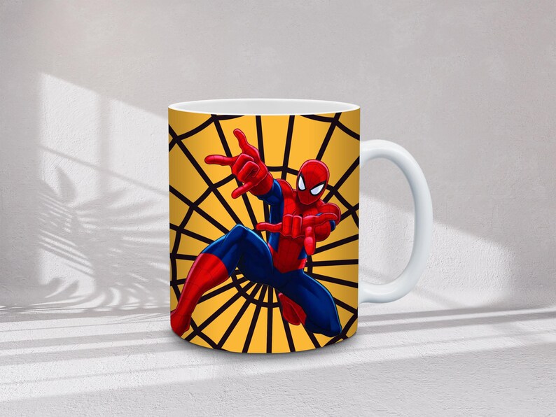 May include: White ceramic mug featuring a colorful illustration of Spider-Man in a dynamic pose. The background is a yellow spiderweb design. The superhero is depicted in his classic red and blue suit.