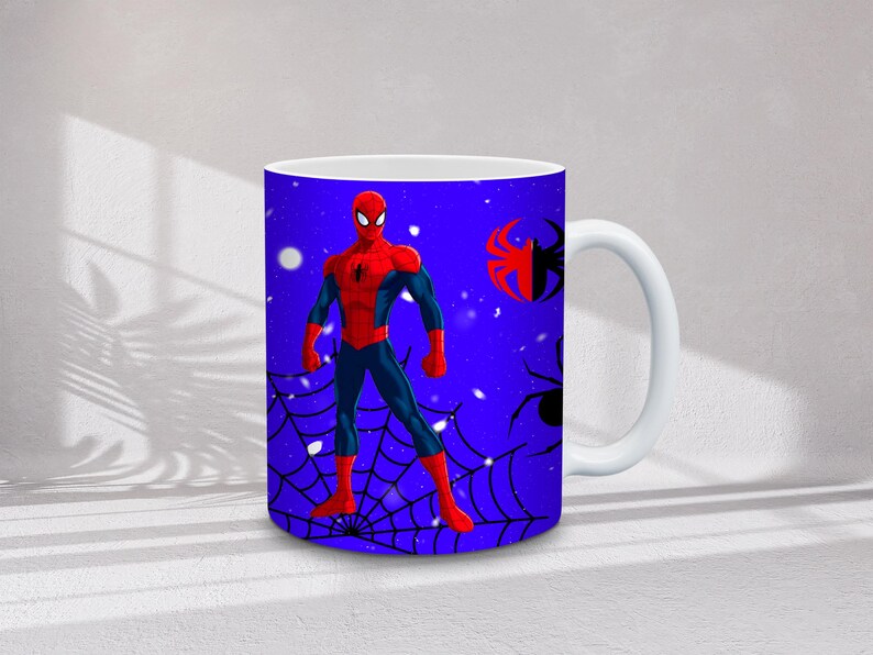 May include: White ceramic mug featuring a vibrant illustration of Spider-Man in his iconic red and blue suit. The design includes a spider web and spider graphics against a blue background. The mug has a white handle.