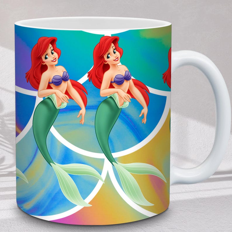 Puede incluir: Taza de cer&aacute;mica blanca con una colorida ilustraci&oacute;n de una sirena con cabello rojo, un sujetador de concha p&uacute;rpura y una cola verde. El fondo tiene un dise&ntilde;o abstracto vibrante con tonos azules, amarillos y morados. La taza tiene un asa blanca.
