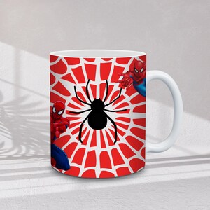 May include: White ceramic mug featuring a red and white spiderweb design with a black spider in the center. The mug also features illustrations of Spider-Man in his red and blue suit.