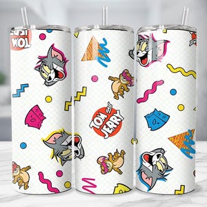 May include: White tumbler featuring a repeating pattern of Tom and Jerry cartoon characters, cheese, and geometric shapes in bright colors. The tumbler includes a straw and the words "Tom" and "Jerry".