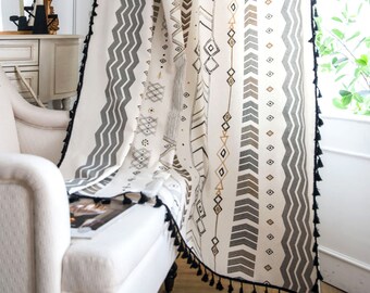 Peut inclure: Rideaux blancs avec des glands noirs et un motif géométrique en noir, gris et or. Le motif comprend des zigzags, des flèches et des diamants.