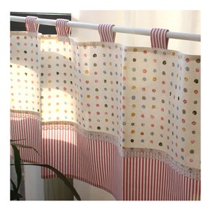 May include: A pair of white valance curtains with a polka dot pattern in shades of pink, blue, green, and yellow. The bottom of the curtains feature a red and white striped fabric with a white lace trim.