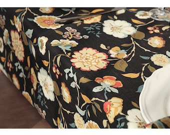 May include: Black tablecloth with a floral pattern in shades of yellow, red, white, and blue. The tablecloth is made of a soft, textured fabric and features a variety of floral designs.