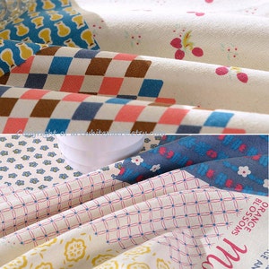 K&ouml;nnte beinhalten: Ein Patchwork-Stoff mit verschiedenen Mustern, darunter florale, karierte und geometrische Designs. Der Stoff ist in Blaut&ouml;nen, Rosa, Gelb und Braun gehalten. Der Stoff ist gefaltet und hat eine strukturierte Oberfl&auml;che.