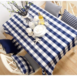 May include: A blue and white checkered tablecloth with a white vase of branches, a bottle of wine, two wine glasses, and a plate with a starfish on a white table.