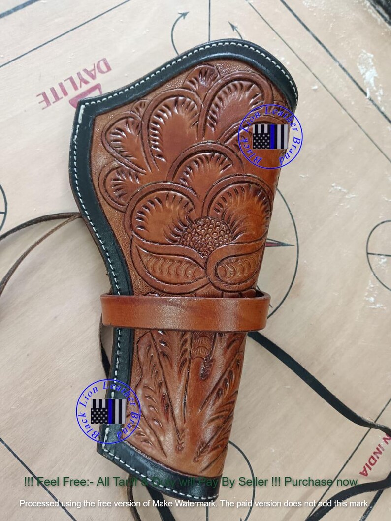 Pode incluir: Uma coldre de couro castanho com intrincados desenhos florais e de folhas. Possui uma borda preta com costura branca e uma presilha de cinto castanha. Uma correia preta est&aacute; presa. O texto "Lion Black Brand" &eacute; vis&iacute;vel.