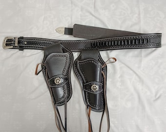 May include: Black leather western gun belt and double holster set. The belt features a silver buckle and decorative stitching. Each holster has a silver star emblem and leather ties. The set is designed for a classic cowboy look.
