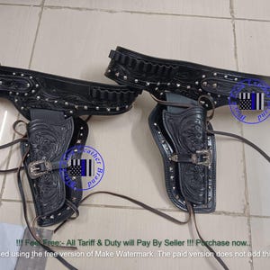 Könnte beinhalten: Schwarzes Leder-Gürtel- und Pistolenholster-Set. Die Holster weisen aufwendige florale Muster, silberfarbene Nieten und dekorative Schnallen auf. Das Set enthält einen Gürtel mit Patronenschlaufen und ein passendes Holster.