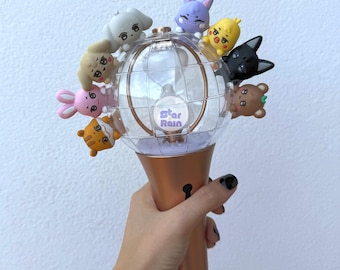 May include: A light-up concert wand with a clear globe and a bronze-colored handle. The globe is adorned with small, colorful cartoon animal figures. The text "Star Rain" is visible on the globe.