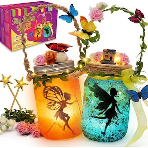 May include: A fairy lantern craft kit featuring two glass jars with fairy silhouettes, one orange and one blue, illuminated by internal lights. The jars are decorated with artificial flowers, butterflies, twine handles, and small figurines.