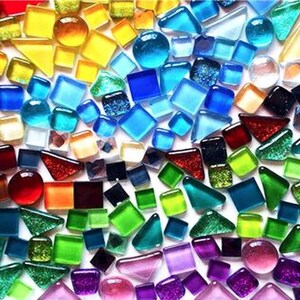 May include: A vibrant assortment of colorful glass mosaic tiles in various shapes, including squares, triangles, and circles. The tiles display a spectrum of colors, ranging from yellow and orange to blue, green, and purple. The mosaic pieces are arranged closely together.