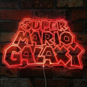 May include: A red neon sign displaying the text "SUPER MARIO GALAXY" in a distinctive font. The sign is set against a brick wall. The neon light emits a bright, warm glow.