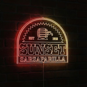 May include: A neon sign displaying "SUNSET SARSAPARILLA" in a rectangular shape with a semi-circular top. The sign features a barrel graphic and the text "EST 1918". The sign is red and yellow and is mounted on a brick wall.