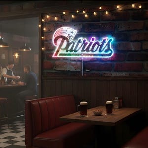 May include: Neon sign with the word "Patriots" in a colorful font, mounted on a brick wall. The sign is illuminated with a vibrant glow, and the image captures a cozy bar setting with a red booth and a table with two mugs of beer.
