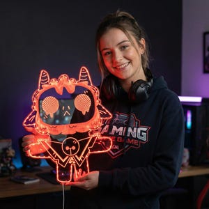 May include: An illuminated orange LED gaming light shaped like a cartoon character. The light features a distinctive face and body design. The character is holding the light. The light is connected to a power supply.