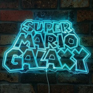 May include: A neon sign displaying the text "SUPER MARIO GALAXY" in a vibrant blue hue. The sign is set against a brick wall. A white power cable is visible. The sign's design is a nod to the popular video game.