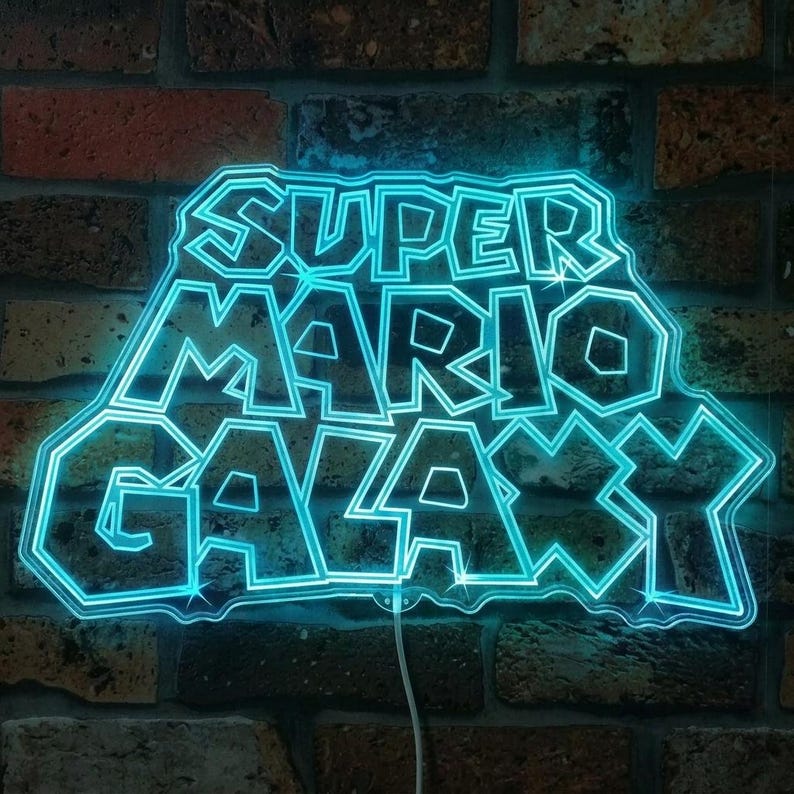 May include: A neon sign displaying the text "SUPER MARIO GALAXY" in a vibrant blue hue. The sign is set against a brick wall. A white power cable is visible. The sign's design is a nod to the popular video game.