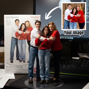 May include: A family figurine, featuring a man, a woman, and a young woman, all in casual attire, embracing. The figurine is on a clear base, with a box in the background. The box has Japanese text and a drawing.