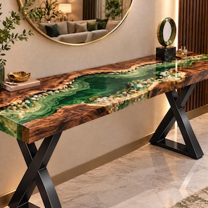 May include: A long console table featuring a natural wood slab edge with a central river-like inlay of translucent green resin and embedded white stones. The table is supported by two black metal X-shaped legs, creating a sturdy base for the top.