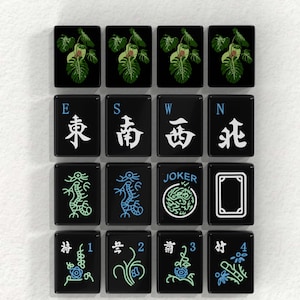 a collection of black and white tiles with various symbols and designs, including images of plants, dragons, and a joker.