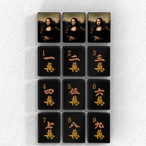 a collection of tiles, each featuring a different character or symbol. The tiles are arranged in a grid pattern, with each tile displaying a unique character or symbol. The tiles are black with gold accents, creating a visually striking contrast. The image does not contain any text, and the arrangement of the tiles suggests a deliberate design choice.