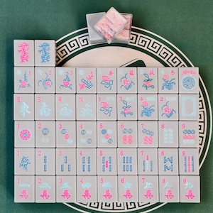 A grid of gray tiles with various colorful designs and symbols, including numbers and shapes, arranged on a green surface.