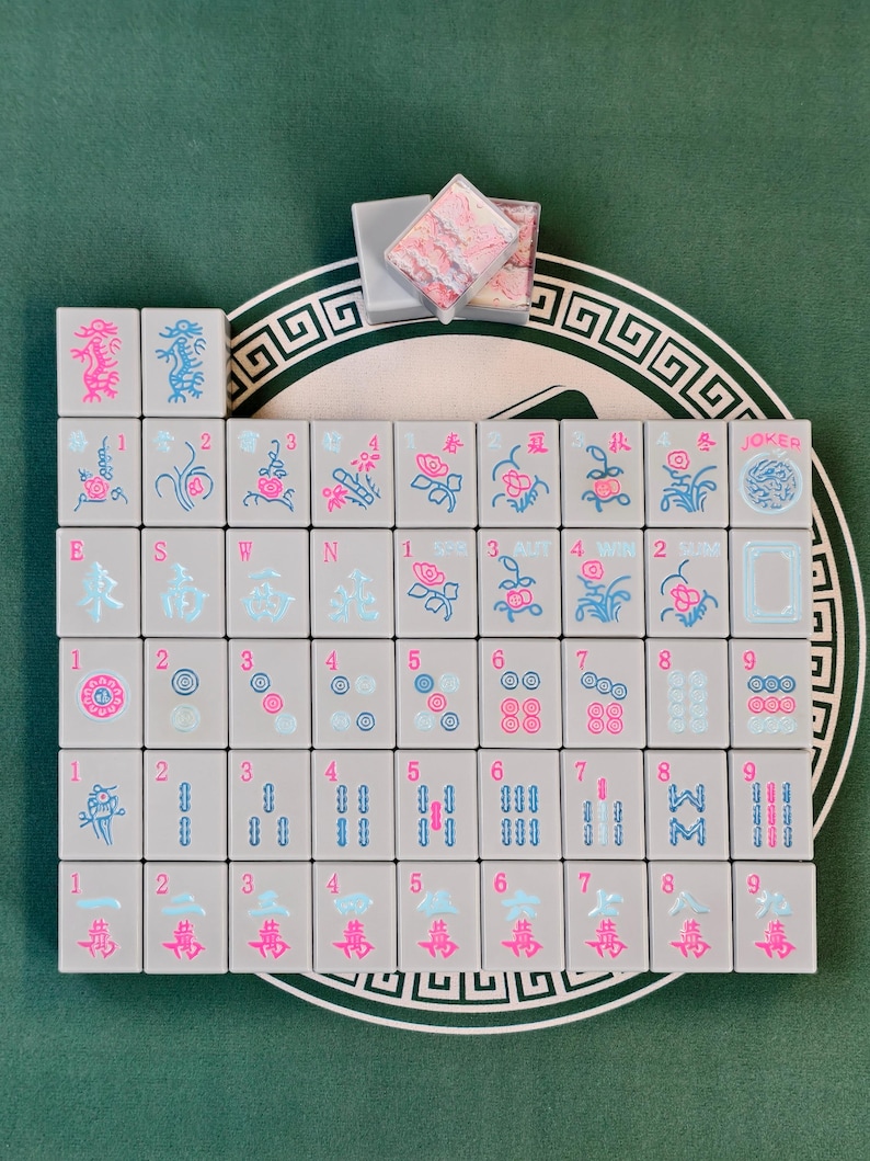 A grid of gray tiles with various colorful designs and symbols, including numbers and shapes, arranged on a green surface.