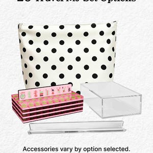 a set of travel-related items, including a polka dot bag, a pink and black box, and a clear plastic container. The text above the items reads "20 Travel MJ Set Options" and below the items, it states "Accessories vary by option selected."