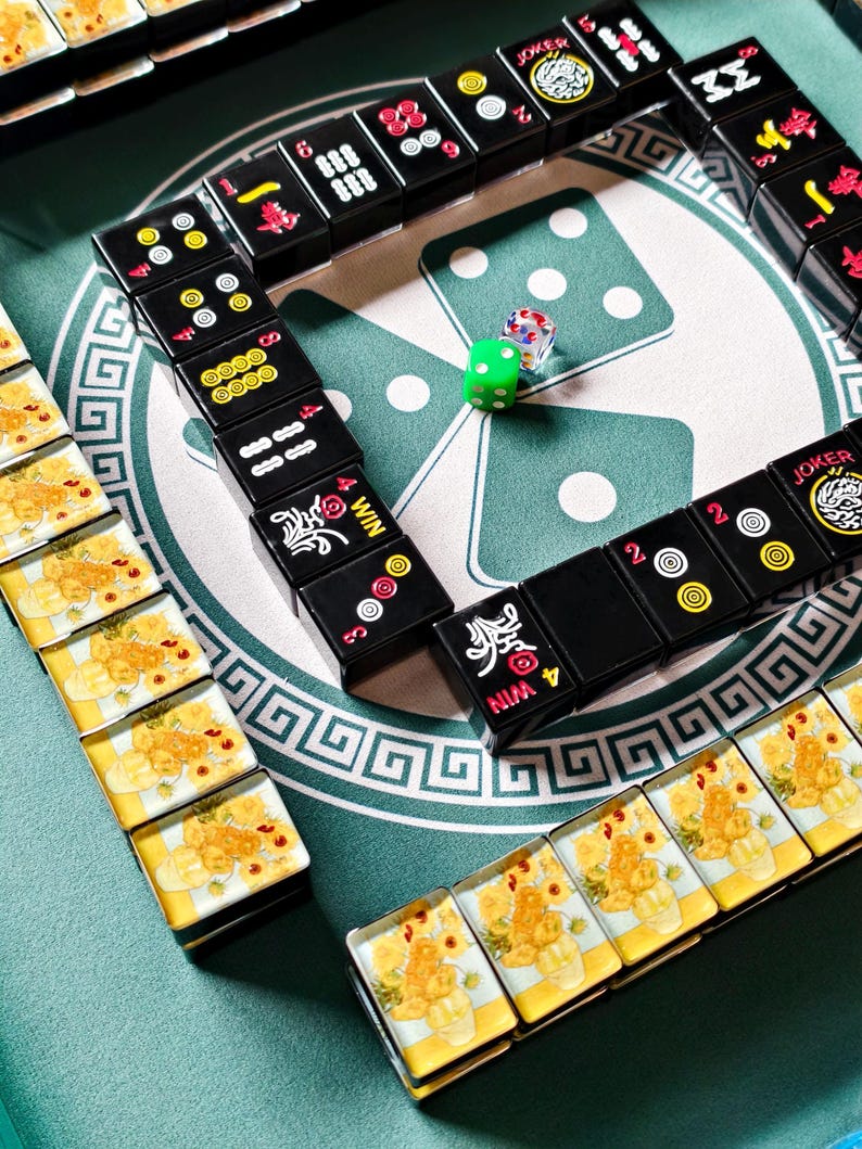 A domino game set up on a green table, with multiple dominoes arranged in a pattern and a single green die placed in the center.