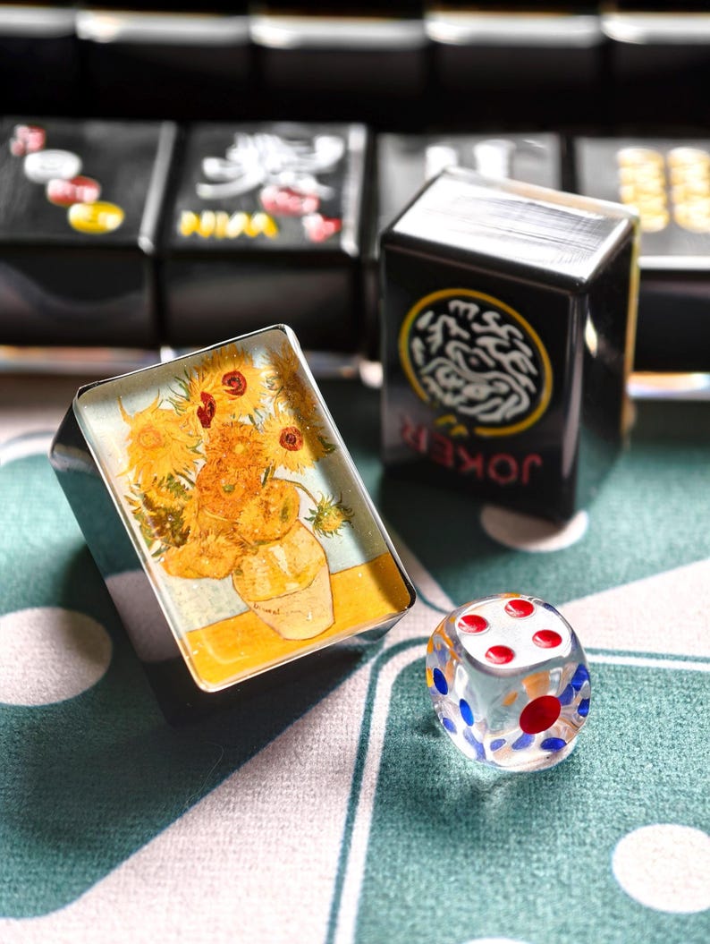 a playing card with a sunflower design, a glass dice, and a deck of playing cards on a table.