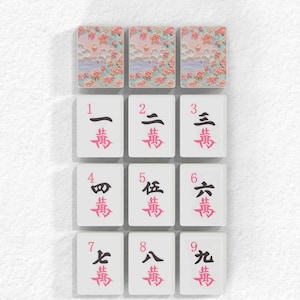 nine tiles, each with a different character or symbol on it. The tiles are arranged in a grid pattern, with three tiles on the top row, three on the middle row, and three on the bottom row. The characters on the tiles are in a foreign language, which suggests that the image is a collage of multiple images. The tiles are not described individually, and the phrase "less than 500 characters" implies that the image contains fewer than 500 characters.