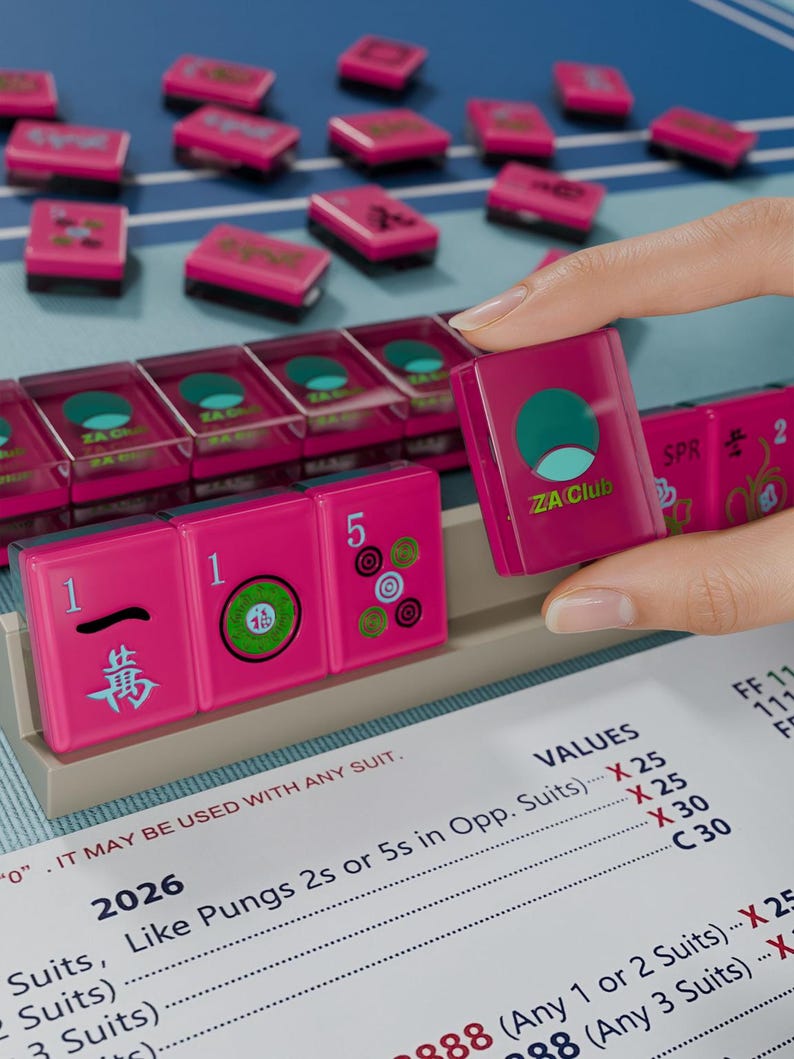 A hand is holding a pink tile with a logo, while a table with a list of items is visible in the background.