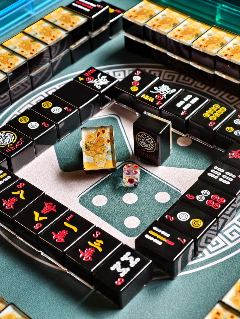 a collection of black and yellow tiles arranged in a grid-like pattern, with some of the tiles featuring Chinese characters. There are also two dice and a small figurine on the surface, suggesting a game of mahjong or a similar tile-based game.