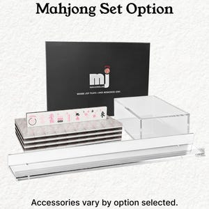 The image is an advertisement for a "Mahjong Set Option" that includes a black box with the "Mahjong" logo and the text "Where Joy Flats-And Memories Stax." The set includes various accessories, and the image emphasizes that accessories vary by option selected.