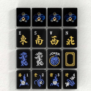 a collection of black tiles with various symbols and designs, including a joker, winds, dragons, and a flower.