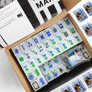 a box containing a set of mahjong tiles and a set of playing cards, both in a cardboard box.