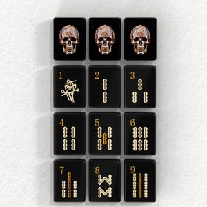 a collection of black tiles with gold designs, arranged in a grid pattern. Each tile has a unique design, including skull motifs and numbers. The tiles are arranged in a visually appealing manner, creating a striking contrast against the white background.