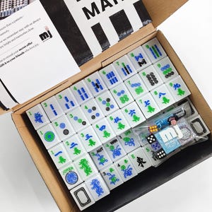 a box containing a set of mahjong tiles and accessories, including a set of tiles and a set of dice.