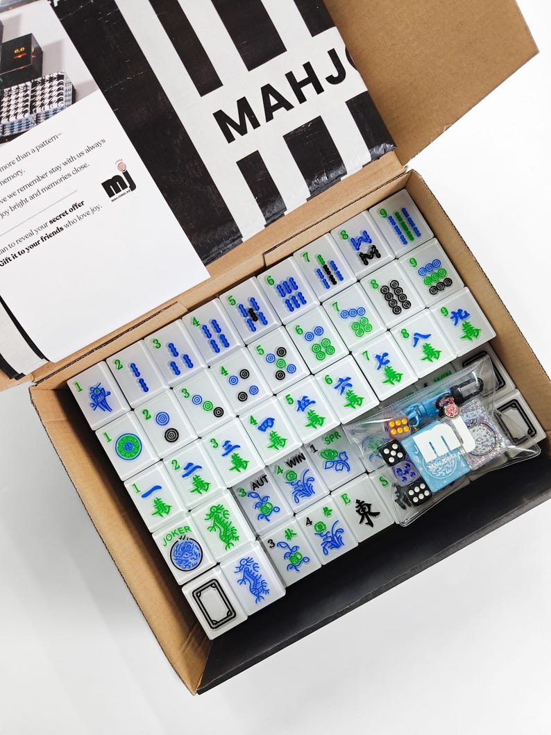 a box containing a set of mahjong tiles and accessories, including a set of tiles and a set of dice.