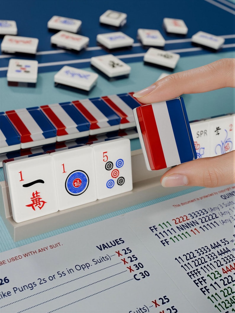A hand is holding a red, white, and blue tile in front of a table with a blue and white checkered pattern.