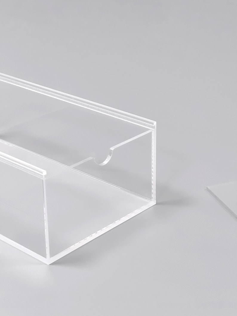 A transparent, clear plastic box with a cutout on the side, sitting on a plain white surface.