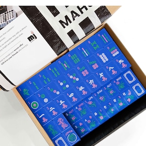 a box containing a set of mahjong tiles, with the tiles in various colors and designs.