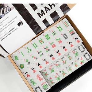 a box containing a Mah Jong set, which is a traditional Chinese tile-based game. The box is open, revealing the game components inside.