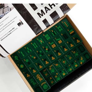 a box containing a set of mahjong tiles, with the box open to reveal the tiles inside.