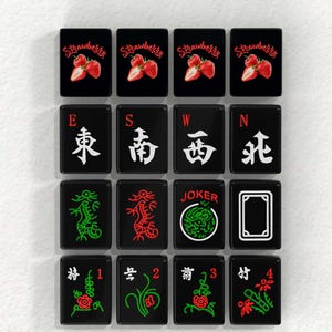 a collection of black and white tiles with various symbols and text, including images of strawberries, dragons, and the word "JOKER".
