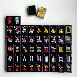 A grid of black and red tiles with various symbols and numbers, along with a small black box with a yellow picture on top.