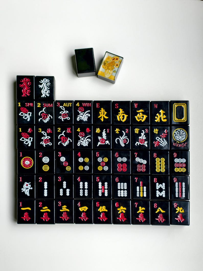 A grid of black and red tiles with various symbols and numbers, along with a small black box with a yellow picture on top.